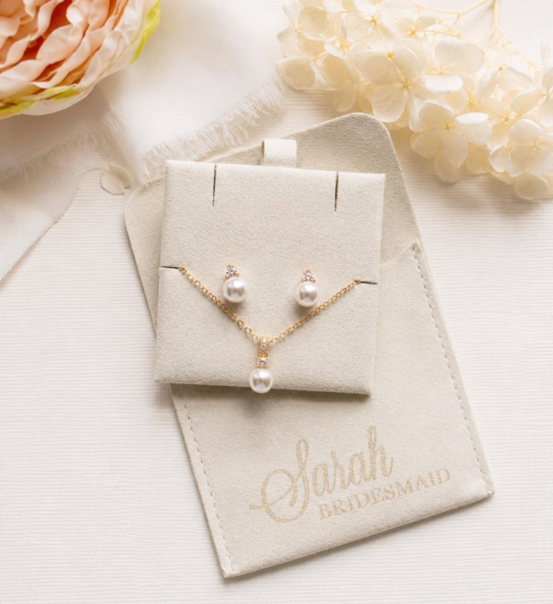 PinkPeonyBridesmaids pearl stud earrings beside a personalized name pouch