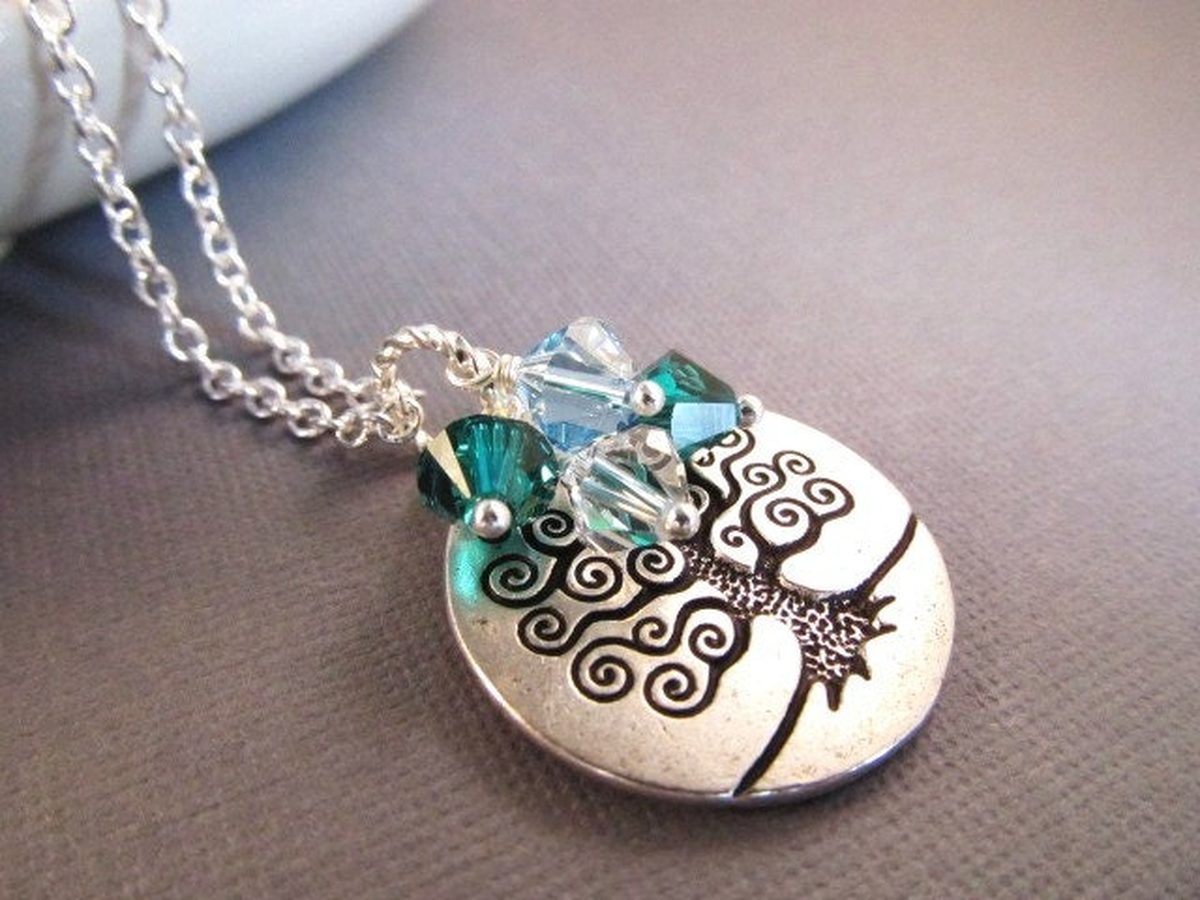 Silver-toned tree of life pendant necklace with green and blue crystal accents on a fine chain