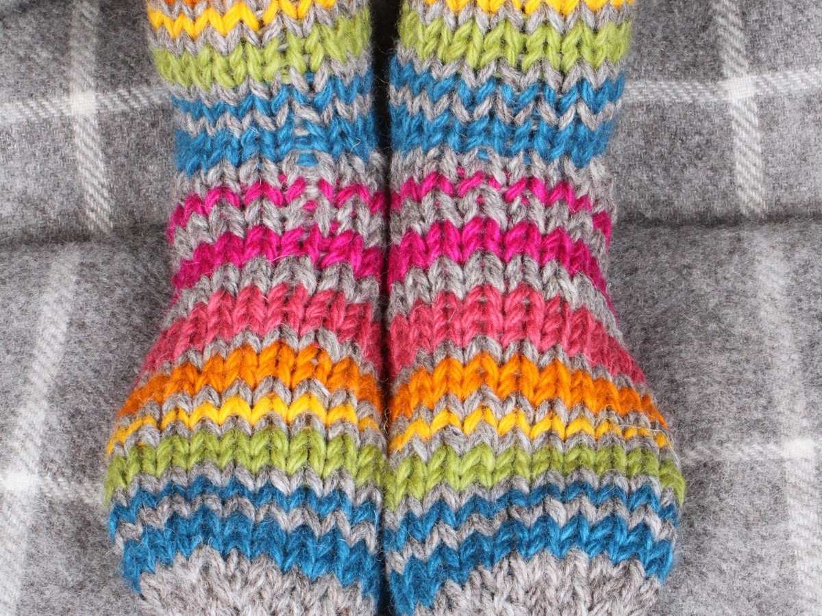 Close-up of chunky knit wool sofa socks with rainbow stripes
