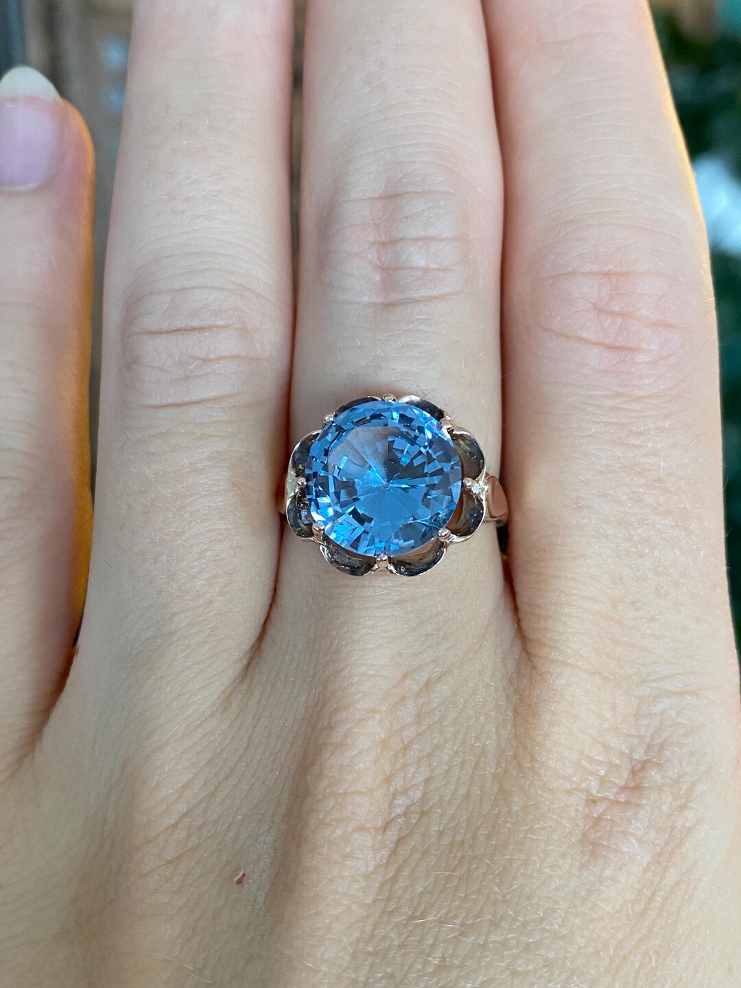 Vintage solid 9k rose gold ring set with a large round blue topaz, worn on a hand