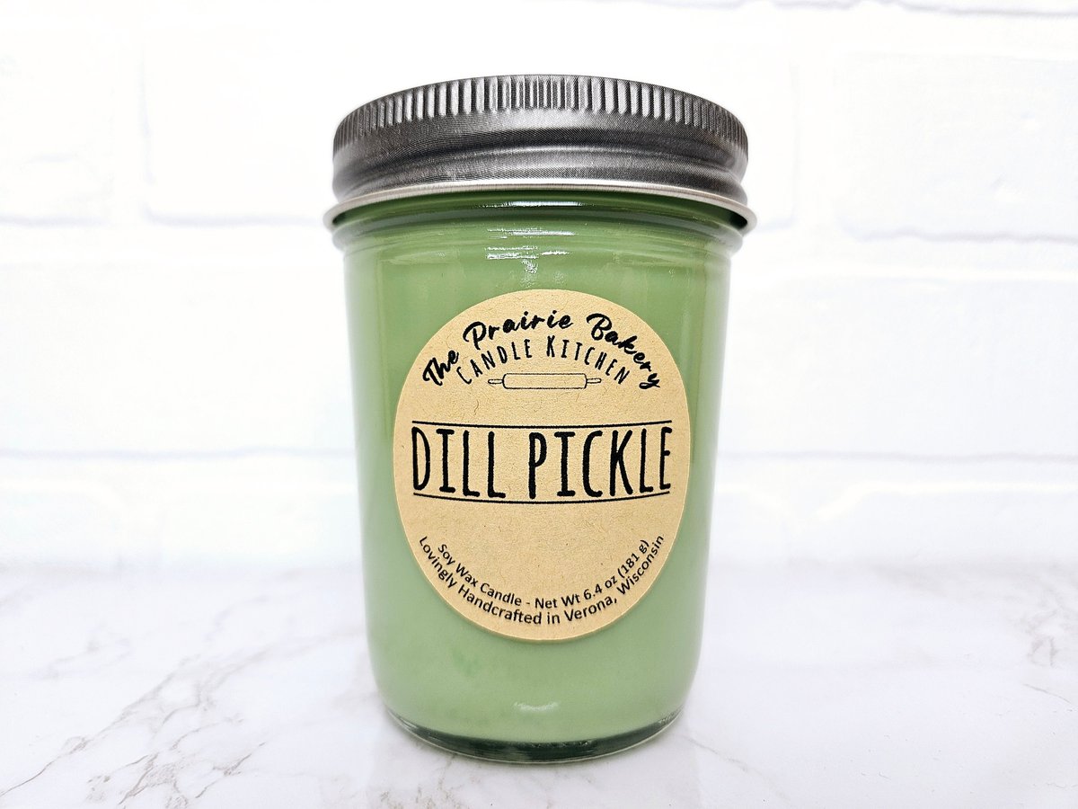 Green dill pickle soy candle in a glass mason jar with a kraft paper label reading Dill Pickle