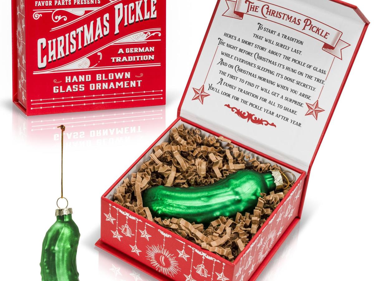 Green glass pickle ornament in a red illustrated gift box with the Christmas pickle story inside the lid